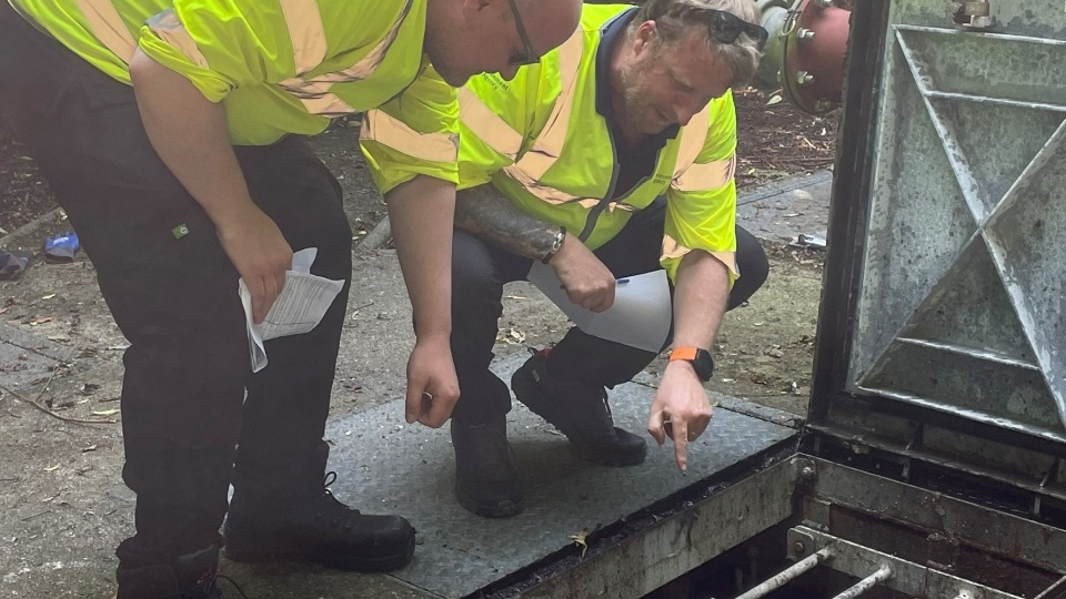 Officers inspecting the wet well at a pumping station to make sure all pumps, chains and floats are in good working order.